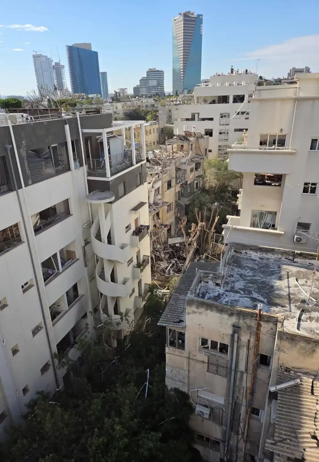 אתר בנייה והריסה של בניינים ישנים בפרויקט פינוי בינוי בלב עיר מודרנית עם גורדי שחקים ברקע.